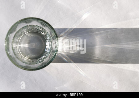 Glass beaker from which padajet sharp shadow, stands on a white background. Empty space for text Stock Photo