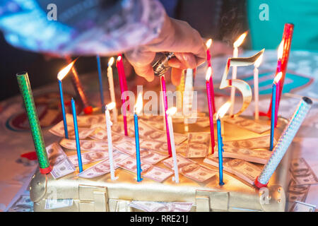 15 years old burns the candle. The dollar cake. man is burning birthday candles . Light candles on the cake to mark the fifth anniversary. Stock Photo
