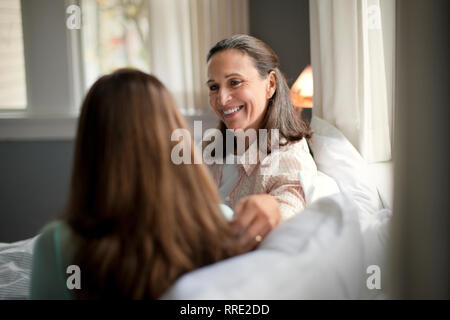 Happy mother and daughter sitting on a sofa. Stock Photo