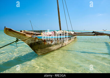 View of an old wooden boat or catamaran, anchored off the Kenyan coast in Africa in the clear sea. Bright blue sky. Stock Photo