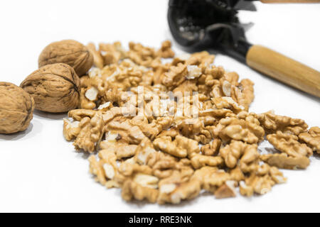 Nutcracker, walnut kernels and whole nutshells closeup macro, isolated on a white background. Dried fruit Stock Photo
