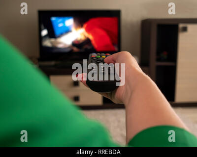 Female hand holds TV remote, rear view Stock Photo