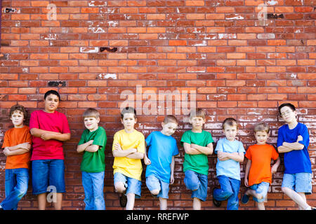 Group of Boys Leaning Against Brick Wall Outside Stock Photo