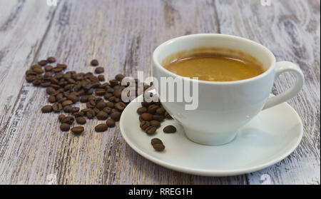 A Cup of fragrant black coffee and a handful of coffee beans on an old wooden table close-up. in the morning to drink. Stock Photo