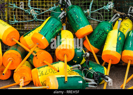 Vinalhaven, Maine, USA - 5 August 2017: Green, yellow and orange buoys with the owners name and numbers are ready to be put in the water above lobster Stock Photo