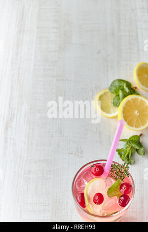In summer, drink berry lemonade cocktail with lemon and ice in a glass. Ice-cold lemonade. Healthy vitamin drink. Copy space. Stock Photo