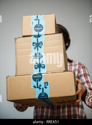 PARIS, FRANCE - DEC 2, 2018: Casual dressed woman holding three Amazon Prime parcel cardboard box stack one above another ready for winter holidays gifts shopping - on time delivery Stock Photo