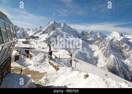 DOMBAI, RUSSIA, FEBRUARY 27, 2018: Monument to a mountain goat on the background of a ski lift and the high peaks of the Caucasus Mountains Stock Photo