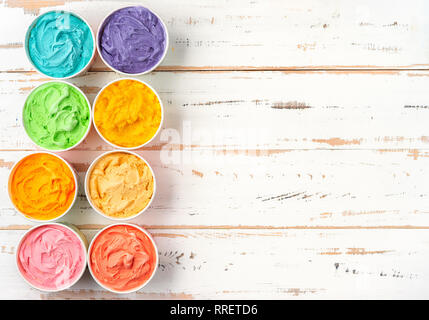 Top view of colorful rainbow ice cream in cups on white wooden background Stock Photo