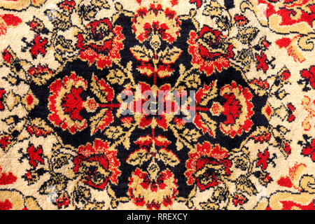 Ornament details of a vintage Persian carpet of vivid red, brown, yellow and black colors. Textile pattern or background Stock Photo