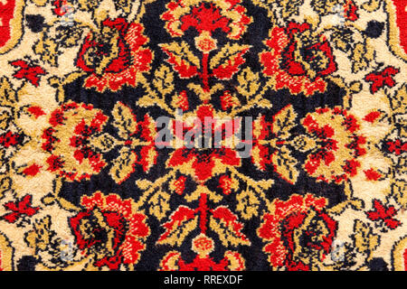 Ornament details of a vintage Persian carpet of vivid red, brown, yellow and black colors. Textile pattern or background Stock Photo
