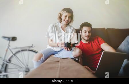 Cheerful couple laying down on the couch with computer Stock Photo