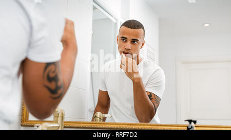 Man looking at mirror and brushing his teeth in bathroom Stock Photo