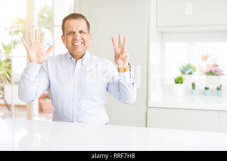 Middle age man sitting at home showing and pointing up with fingers number eight while smiling confident and happy. Stock Photo