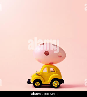Easter egg and toy car on pink background, happy easter day concept. Stock Photo