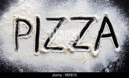 Pizza word written in flour on black table Stock Photo