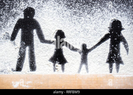 Figure flour in the form of family figures on a black table. Cooking pizza. The concept of family leisure.