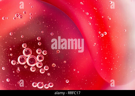 From above closeup many abstract red and pink water bubbles on glass on blurred background Stock Photo