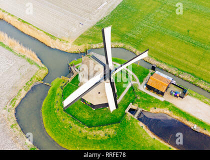 Typical Dutch windmill from the 17th century shot from above with a drone surrounded by a canal in the fields of holland