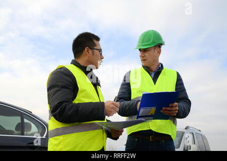 Engineer showing something on the paper to their  boss on newly constructed highway Stock Photo