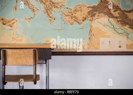 Empty desks at school classroom with world map. Stock Photo