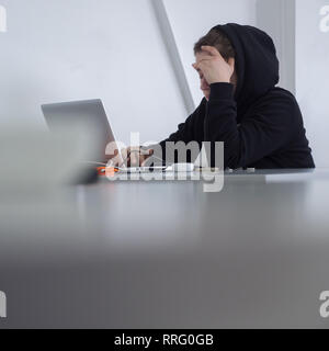 Student at desk. Working female. Woman qualified job. Searching for job. Girl in hoody sits at desk. Modern muslim woman. Refugee looking for job Stock Photo