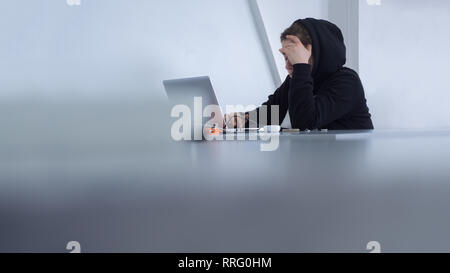 Cyber security concept. yber criminals background. Student preparing to exam. Female working at office. Female in hood sitting at table. Student Stock Photo