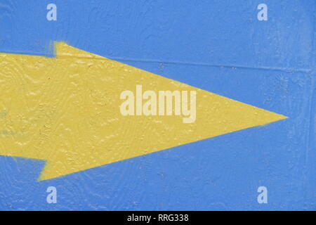 Yellow arrow, direction sign, blue background, painted on wall Stock Photo