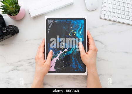 ZAGREB, CROATIA - FEBRUARY 18, 2019: Women hands holding a box of Apple iPad Pro 11 inch surrounded by Apple Pencil 2, computer and camera on white ma Stock Photo