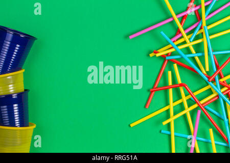 No plastic concept. Single use plastic cups and drinking straws on green background Stock Photo