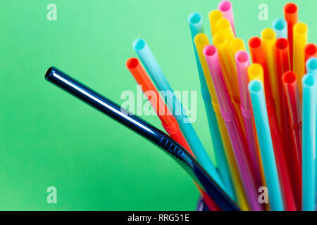 Stainless steel reusable drinking straw with plastic straws on green background Stock Photo