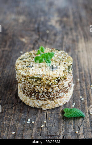 Dessert cereal snacks. Fitness dietary food. Kozinaki with sesame, peanuts, sunflower and pumpkin seeds and chocolate chip on old rustic wooden board, Stock Photo