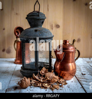 composition of a lantern and a copper pan on wooden background Stock Photo