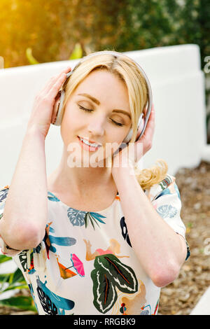 Young pretty girl listens to music on her wireless headphones Stock Photo