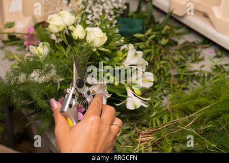 Florist female making a bouquet of different flowers at working table. Stock Photo