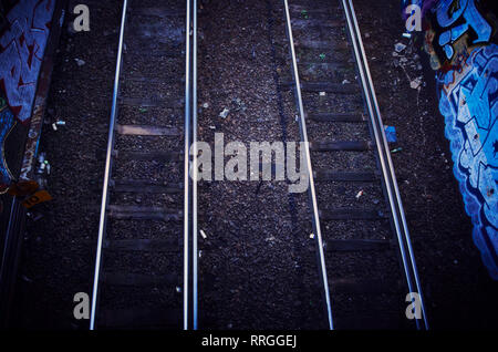 A cool toned set of train tracks along walls of graffiti. Stock Photo