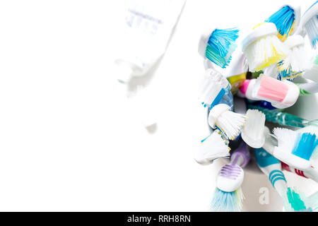 Toothbrushes of different colors in a mug closeup isolated on white background. View from above. Stock Photo