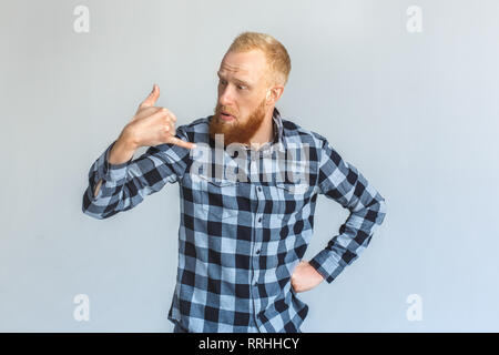 Freestyle. Mature man standing isolated on grey showing call gesture confused Stock Photo