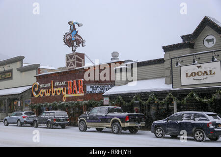 Million Dollar Cowboy Bar Welcome sign and automobiles on a snowy, winter day in western town of Jackson, Wyoming December 24, 2018 Stock Photo