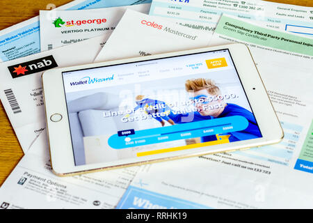 iPad and bills of Australian consumer looking at pay day lender site to pay household bills. Debt-stressed using alternative lenders payday loans Stock Photo