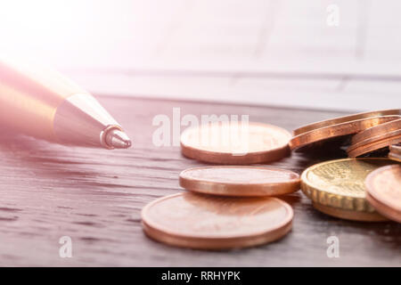 Stack of euro euro coins on old black wooden table. Pen and accounting documents with numbers. Payment planning utility bills Stock Photo
