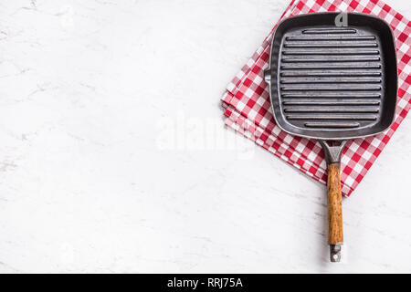 Empty grill pan on marble table with red tablecloth - top of view. Stock Photo