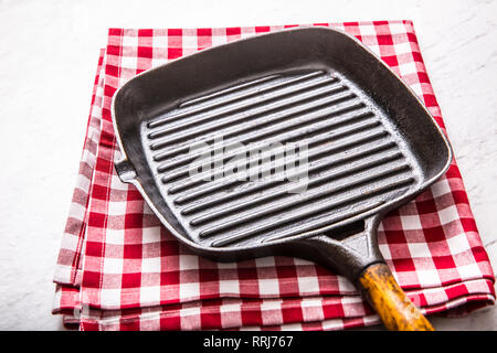Empty grill pan on marble table with red tablecloth. Stock Photo