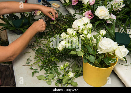 Florist female making a bouquet of different flowers at working table. Stock Photo