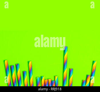 Disposable colorful paper straws on green background Stock Photo