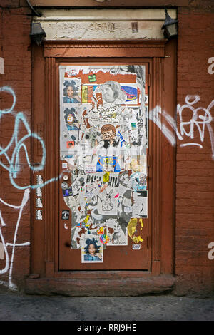 A street art collage of stickers, drawing, graffiti and tagging on a door on Eighth Avenue near 14th Street in Chelsea, Manhattan, New York City