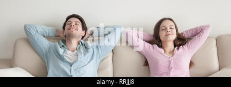 Horizontal image of couple with closed eyes resting on couch Stock Photo