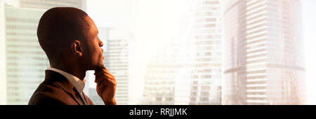 Close up side view black businessman standing near window thinking  Stock Photo