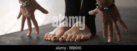 Closeup woman stands on mat doing head to knees pose Stock Photo