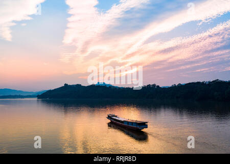 (View from above) Stunning aerial view of a tourists boat sailing on the Mekong river at sunset, Luang Prabang, Laos. Stock Photo
